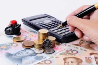 Coins stacked beside a calculator for emergency savings planning
